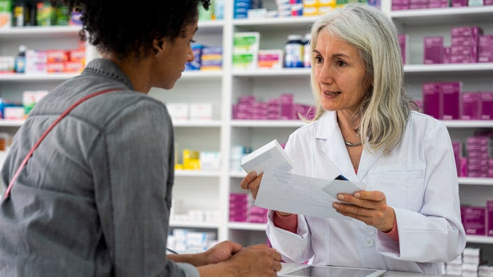 A woman gets a medication consultation with the pharmacist at the counter.