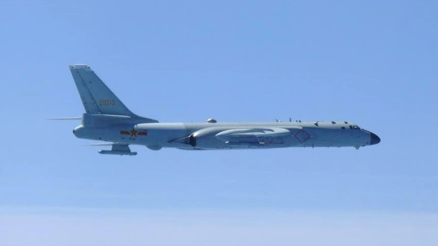 A large bomber flies against a clear sky.