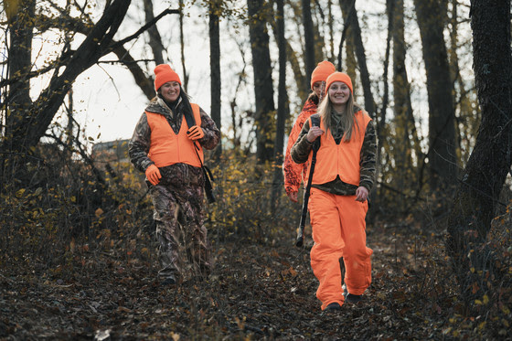 Three female hunters walking in the woods.