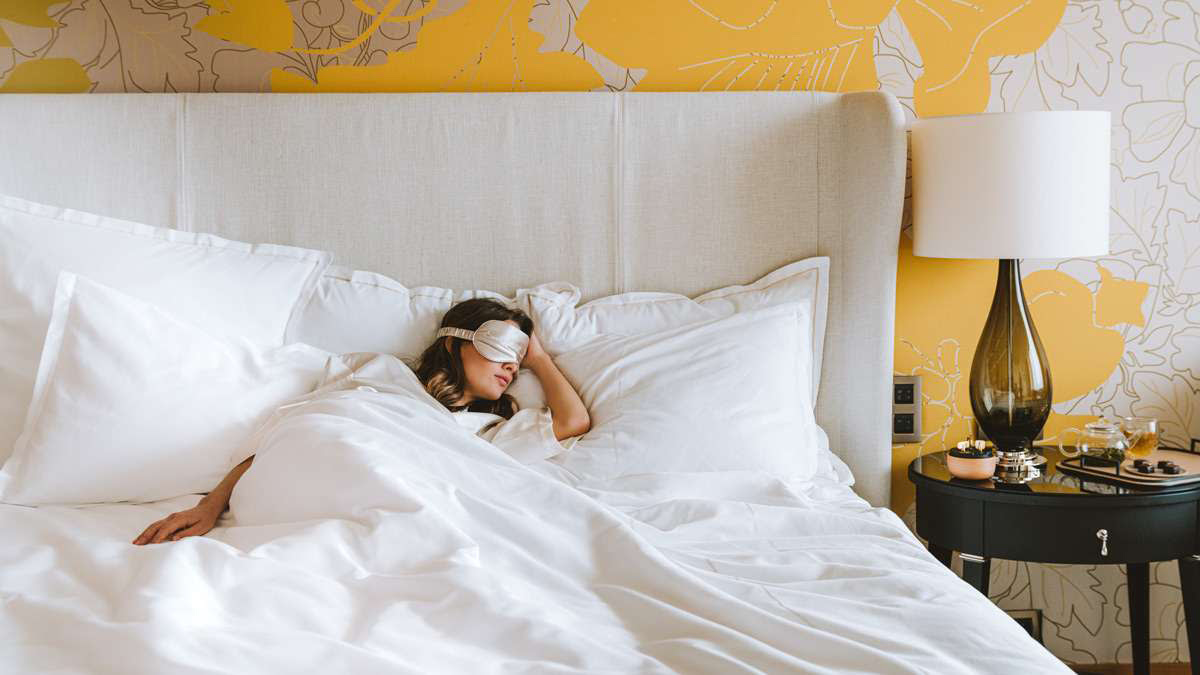 Une femme allongée dans son lit avec un masque pour les yeux au Royal Champagne Hotel.