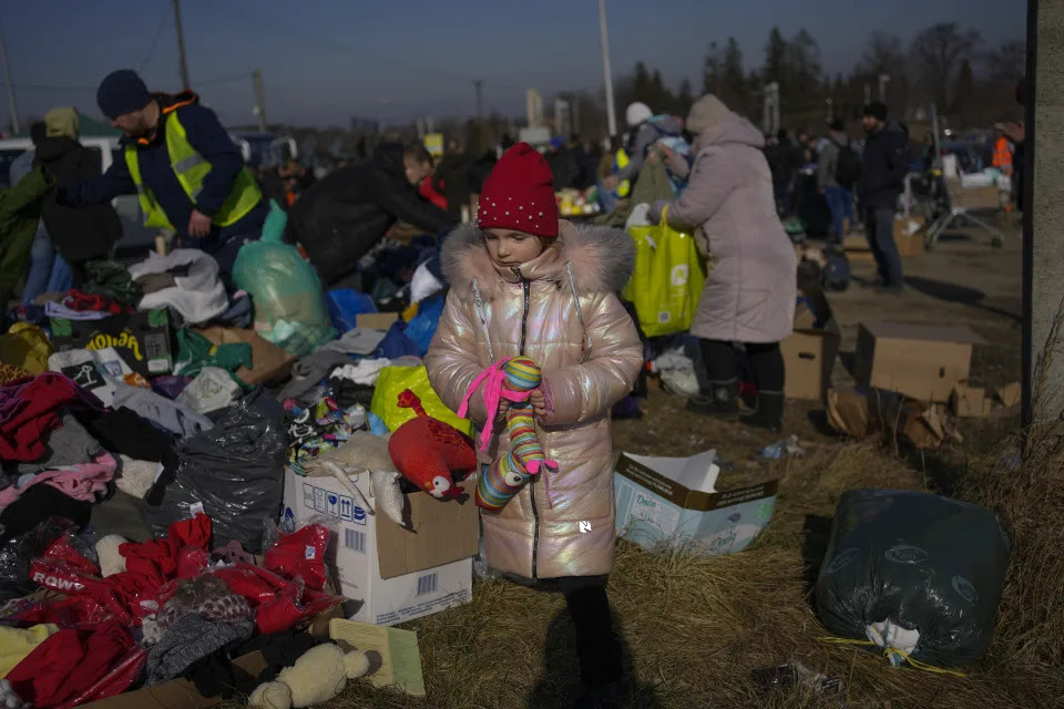 A Ukrainian girl stands near a pile of donated items.