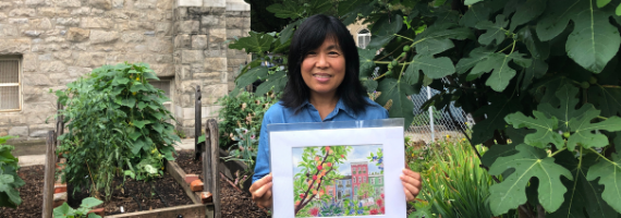 Mee Ling holds her artwork in front of the Union Baptist Church fig tree