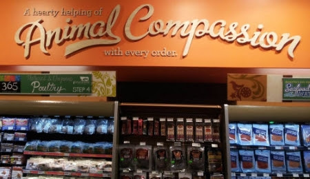 A sign above a Whole Foods meat and seafood section claiming "A hearty helping of Animal Compassion with every order."