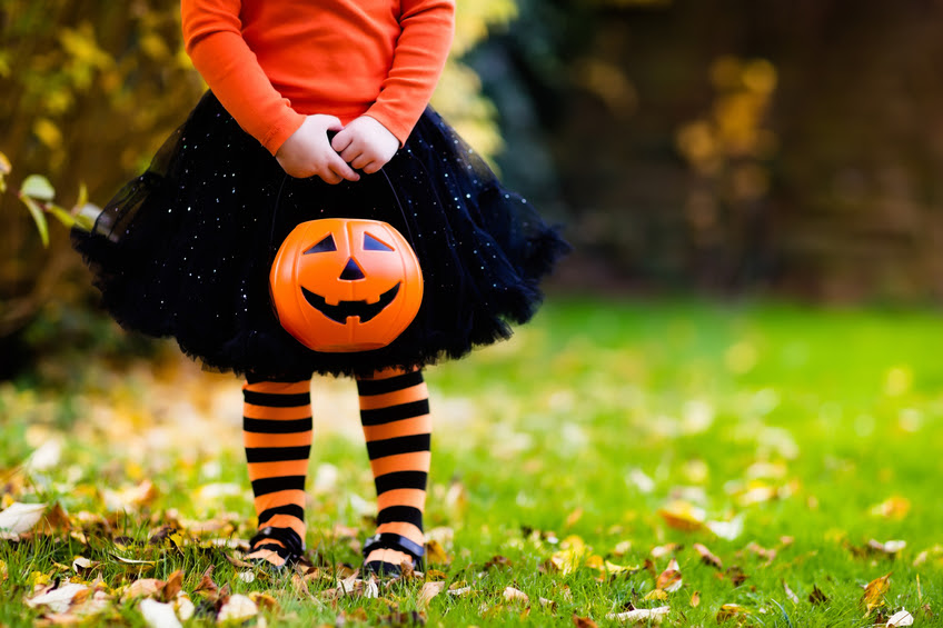 imagen de una niña vestida de bruja con una calabaza para recoger dulces