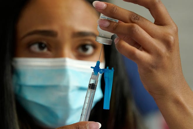 A licensed practical nurse draws a Moderna COVID-19 vaccine into a syringe at a mass vaccination clinic at Gillette Stadium in Foxborough, Mass., in May.