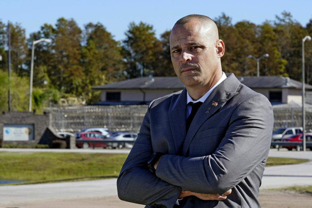Mark Caruso, a former sergeant with Florida corrections, stands outside the Central Florida Reception Center, Monday, Nov. 15, 2021, in Orlando, Fla. The facility is responsible for the intake and classification of many of the inmates in the region. Caruso worked at three prisons in central Florida, and reported inmate beatings and officer misconduct multiple times. He was twice fired and reinstated after blowing the whistle on fellow officers. (AP Photo/John Raoux)