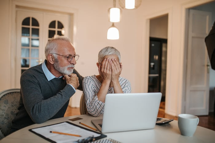 An older couple look over their finances. The woman seems upset