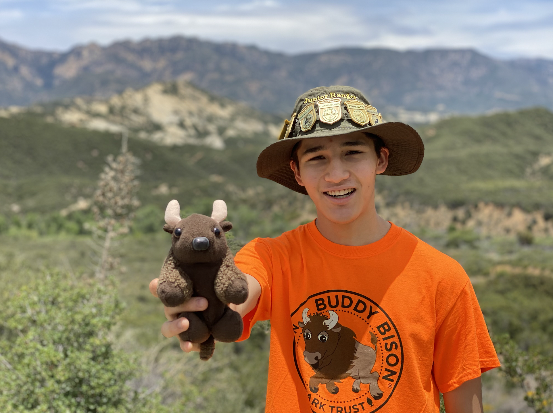 Junior Ranger Tigran Nahabedian holds a small stuffed bison while wearing an orange shirt