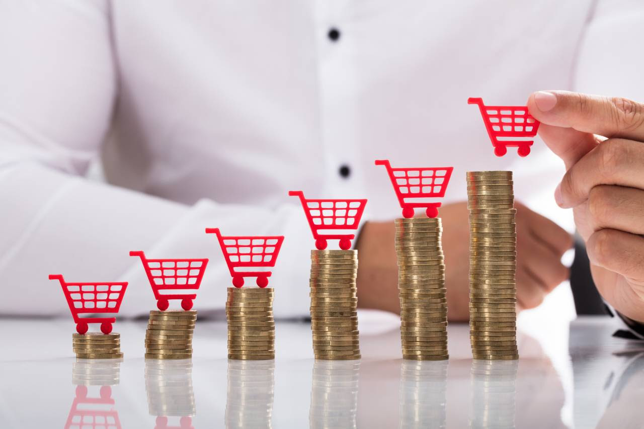 Businessperson placing shopping cart over stacked coins