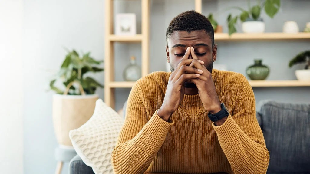 a man holding his temple because he has a metallic taste in mouth and fatigue