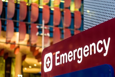 The figure is a photo of a red emergency department sign.