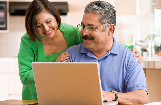 A Hispanic couple looking at their laptop together.