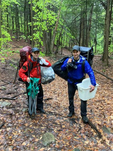 Ranger and Forester carrying bags of trash after cleaning up in the woods