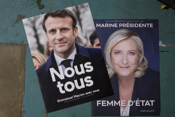 Two campaign posters, one for Macron, saying Nous tous (All of us) and Emmanuel Macron avec vous (Emmanuel Macron with you) and for Le Pen, saying Marine Pr&#xe9;sidente, Femme d&#39;Etat, or Marine, President, Stateswoman.