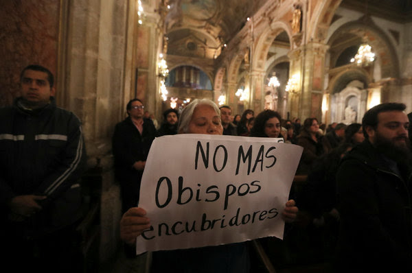 Una manifestante sosteniendo un letrero durante una misa en Santiago este mes