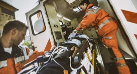 two paramedics loading a patient into the back of an ambulance