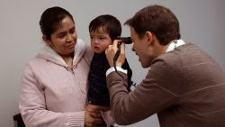 image of a doctor examining a young boy who is in his mother's arms