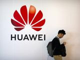 In this Thursday, Oct. 31, 2019, file photo, a man uses his smartphone as he stands near a billboard for Chinese technology firm Huawei at the PT Expo in Beijing. (AP Photo/Mark Schiefelbein, File)
