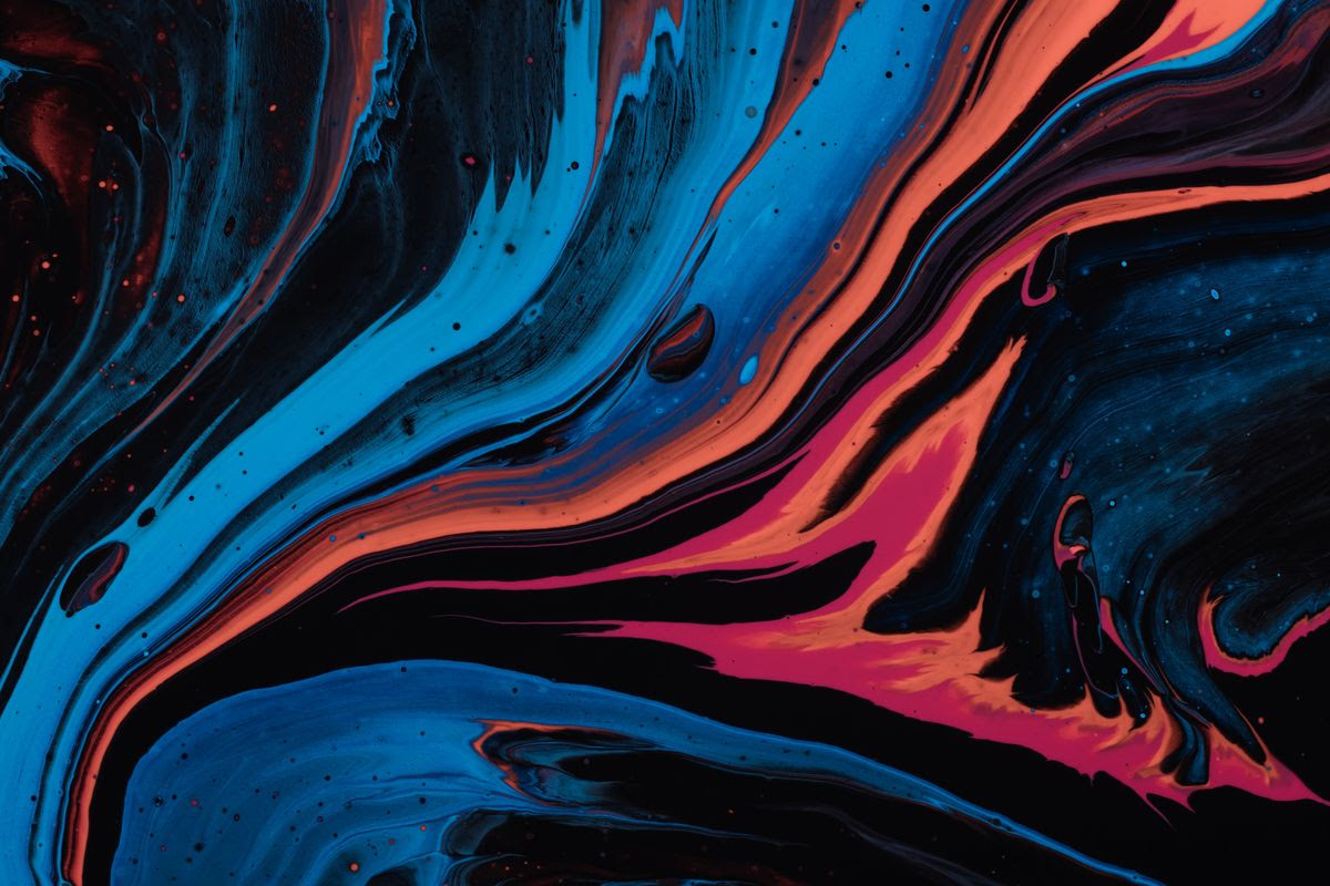 A close-up of a swirl of metallic paint, colors shooting out from left to right, blue, orange, and pink
