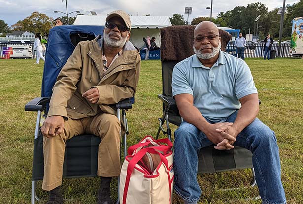 Two men sitting in lawn chairs enjoying the ambiance of the Jazz Roots Festival.