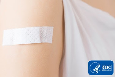 The figure is a photo of an arm with a small bandage on the shoulder with the CDC logo overlaid in the right corner.
