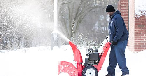 Man pushing a snowblower in the snow.