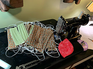 Home made rectangular face masks sit next to a sewing machine