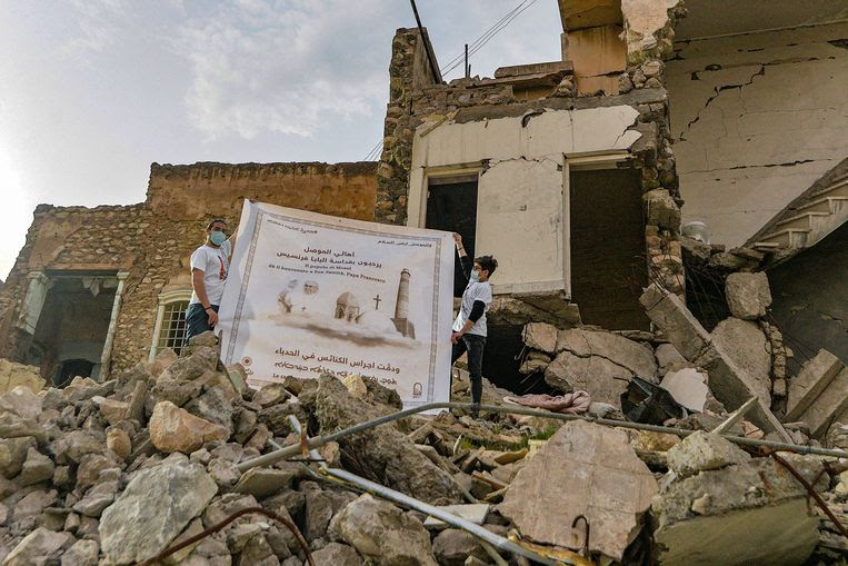 Iraakse jongeren halen een poster van de paus boven in Mosul. Beeld AFP