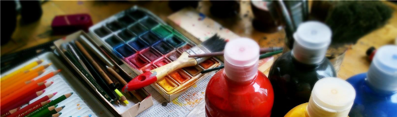 Colorful photos of paint_ brushes_ and colored pencils on a table