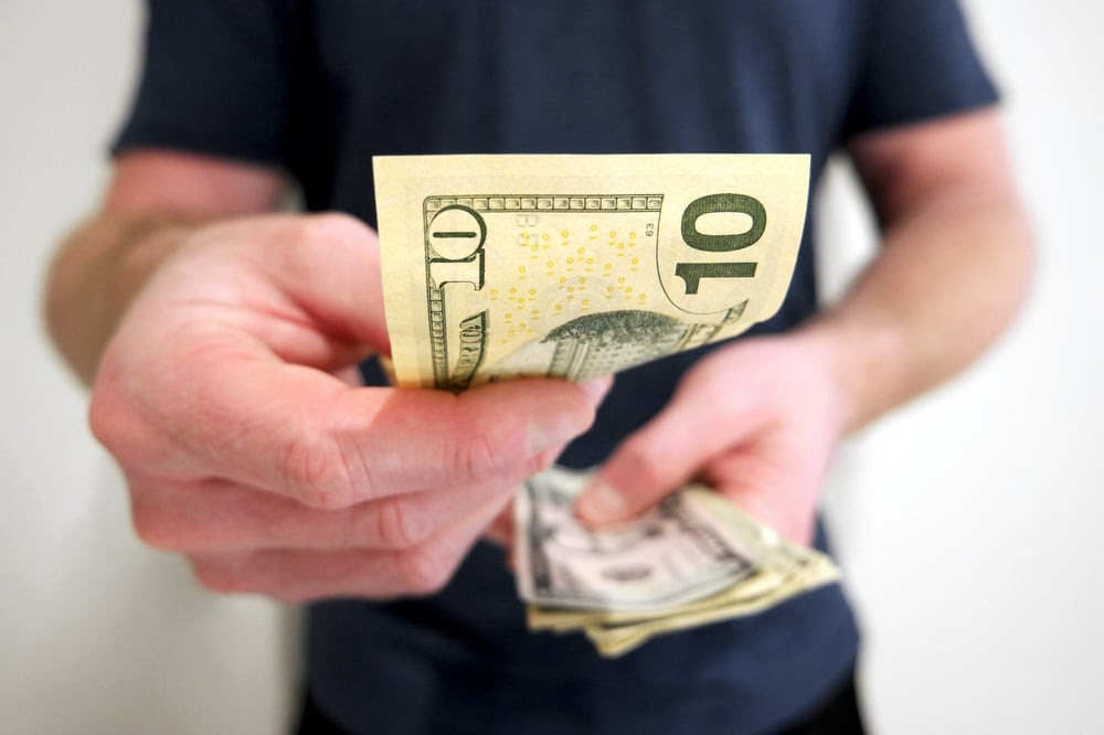 Man handing over a ten dollar bill Man handing over a ten dollar bill