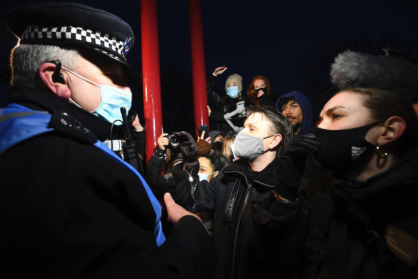 A UK police officer standing in front of a group of women in face masks