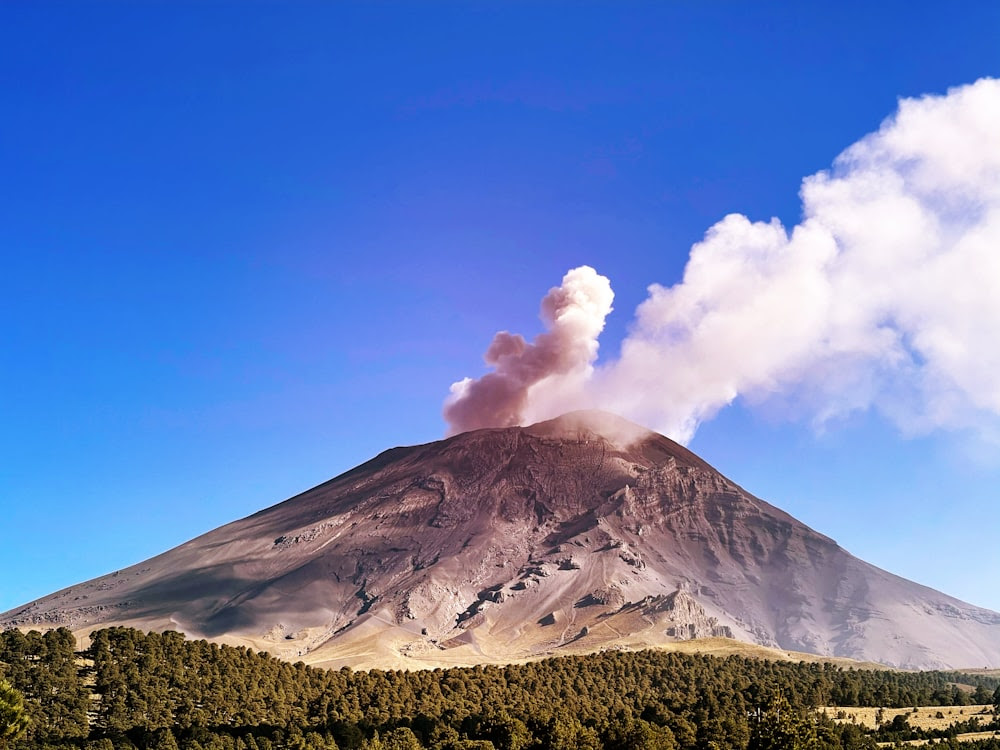 une montagne avec un panache de fumée qui en sort