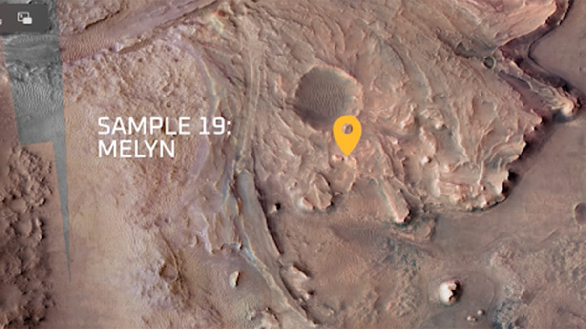 In a satellite view of the surface of Mars, a yellow-orange marker identifies a spot near a crater with the words “Sample 19: Melyn” in white to the left.