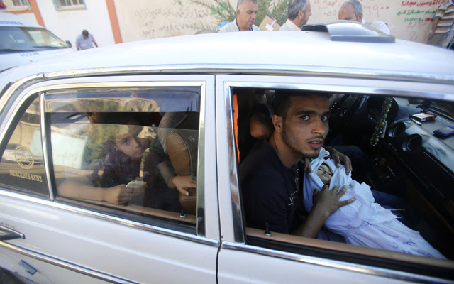 Los familiares de dos niños menores de tres años fallecidos en un bombardeo israelí transportan sus cuerpos en la ciudad de Rafah, este lunes 4 de agosto.