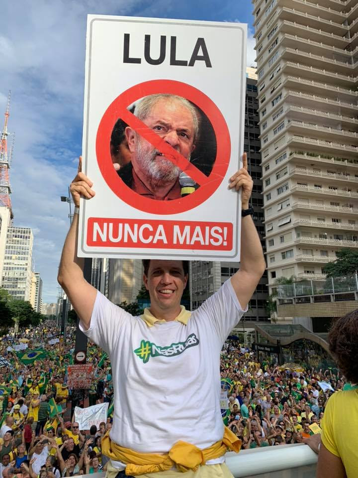 Foto de Bellizia segurando um cartaz com os dizeres "Lula nunca mais", com a foto do ex-presidente e um "x" por cima; Bellizia está em meio a uma multidão na Av.Paulista