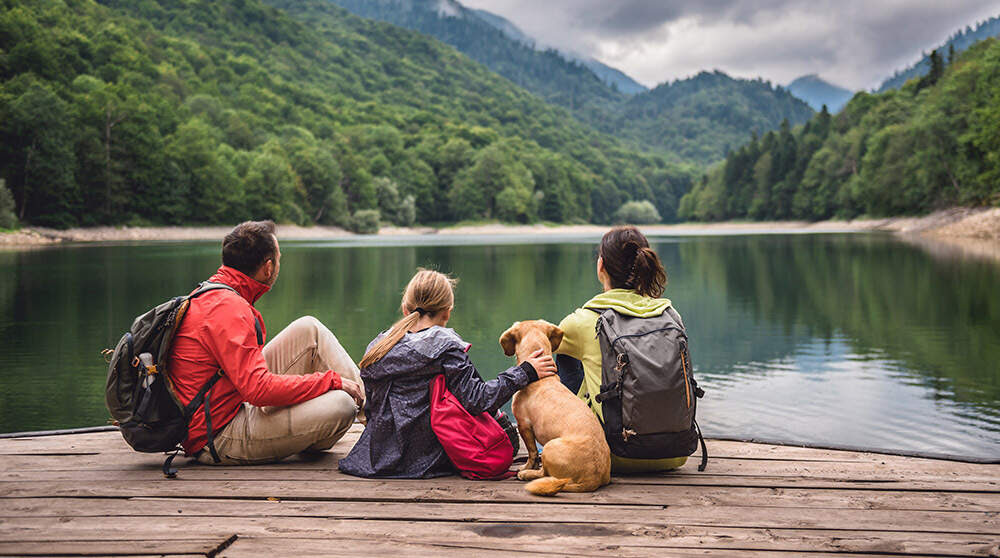 A family and their dog sit by a large body of water.