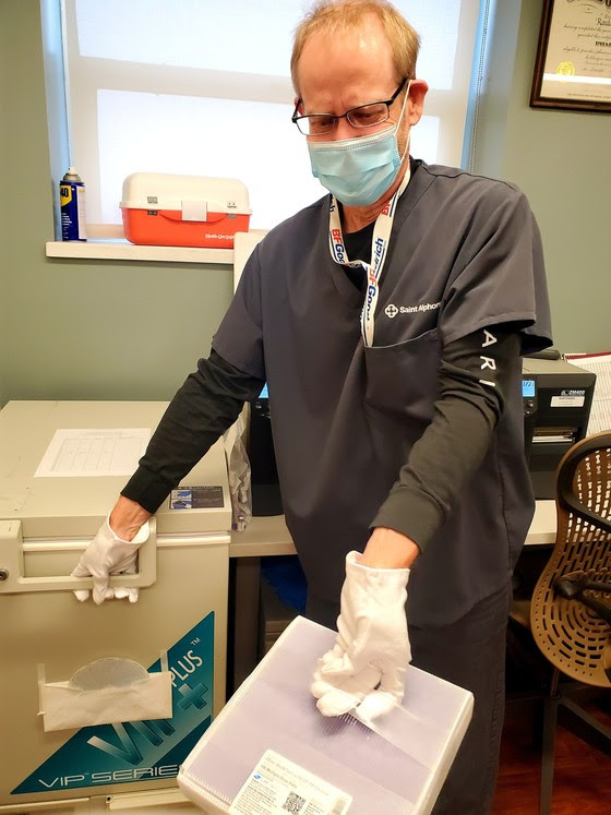 doctor in white coat with mask gloves and vaccine box