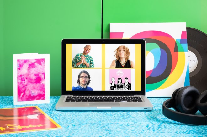 Photograph of a laptop on a desk with a blue patterned surface.  On the laptop screen is a portrait of Gaylene Goud, Rene Matić, Ben Walters and Queer House Party. Next to the laptop are headphones and a pink card. In the background is a LP vinyl record leaning against a bright green cabinet.