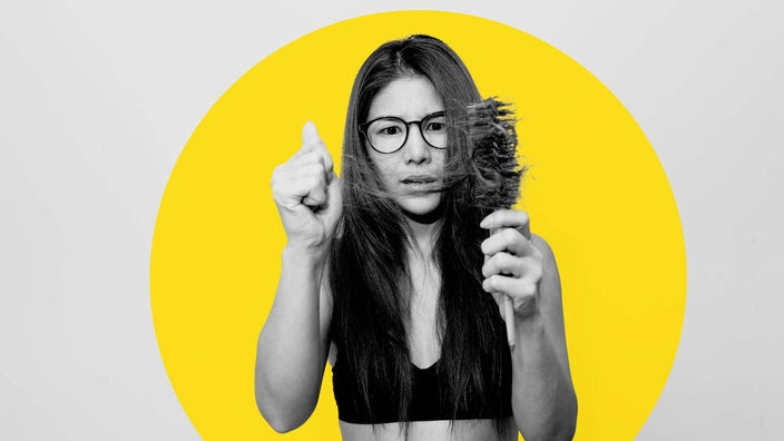 Portrait of a woman with her hair brush and chunks of hair falling out in the brush. She has a concerned look on her face.