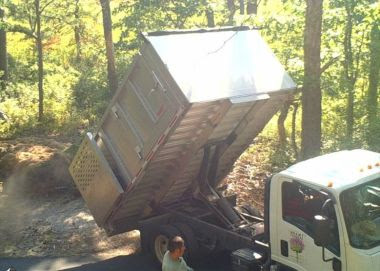 Camera still of a small dump truck dumping debris in a forest area