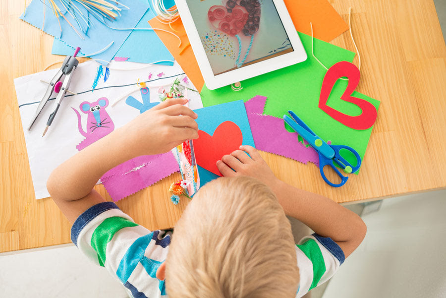 Boy with colorful construction paper, ready to make handmade cards Boy with colorful construction paper, ready to make handmade cards