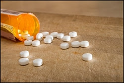 The figure above is a photograph showing pills spilling out from a bottle.