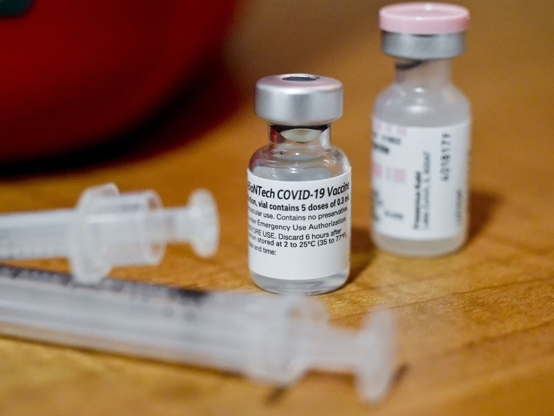 Two syringes with a vial of vaccine and saline.