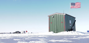 Green ice shanty (building) on frozen lake.
