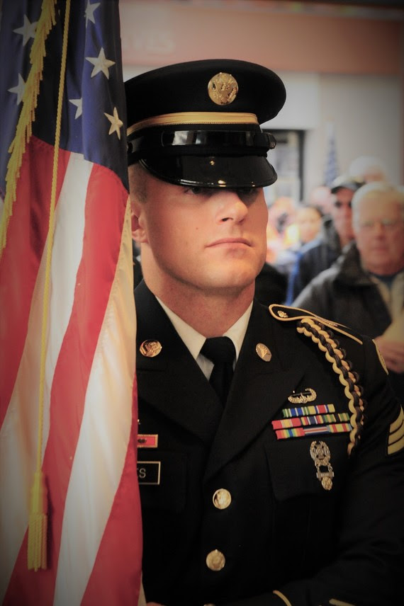 A soldier posts colors during the dedication of Wyoming's Fallen Warrior Memorial on Monday, Veterans Day Observance, and sits near the State Museum in the Capitol Complex