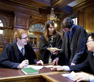 Image of 4 students in our Mock Court Room on Campus.
