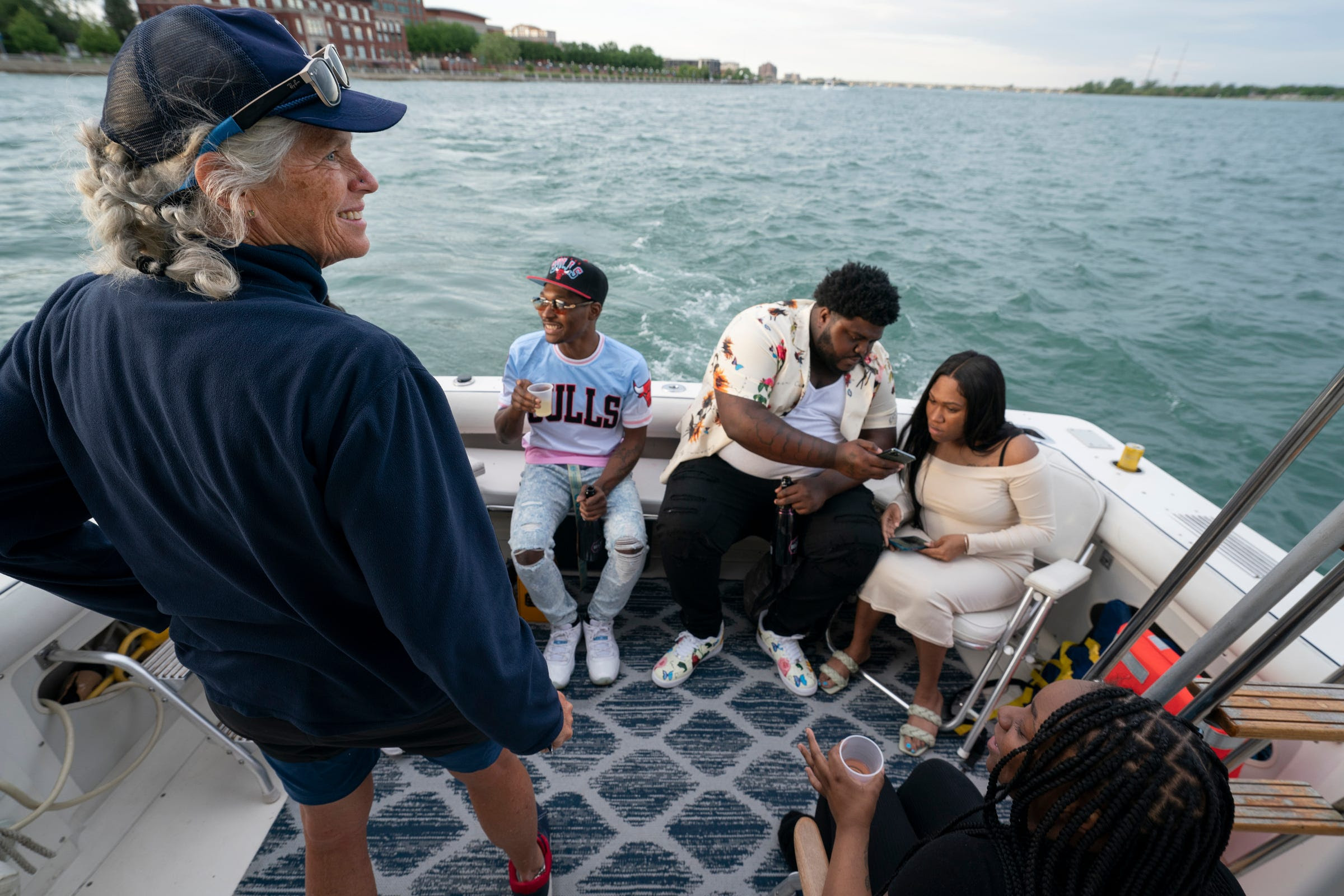 Capt. Ann Perrault, left, hangs out for a minute with clients Jalen Miller, 26, of Detroit, Drew Roberts, 26, of Lincoln Park, Chi Chi Dean, 26, of Detroit, and Lasha Young, 25, of Southfield, during a cruise in the Bertram 33, a boat used by Perrault's company Riverwise Detroit Boat Tours for charter trips on the Detroit River.