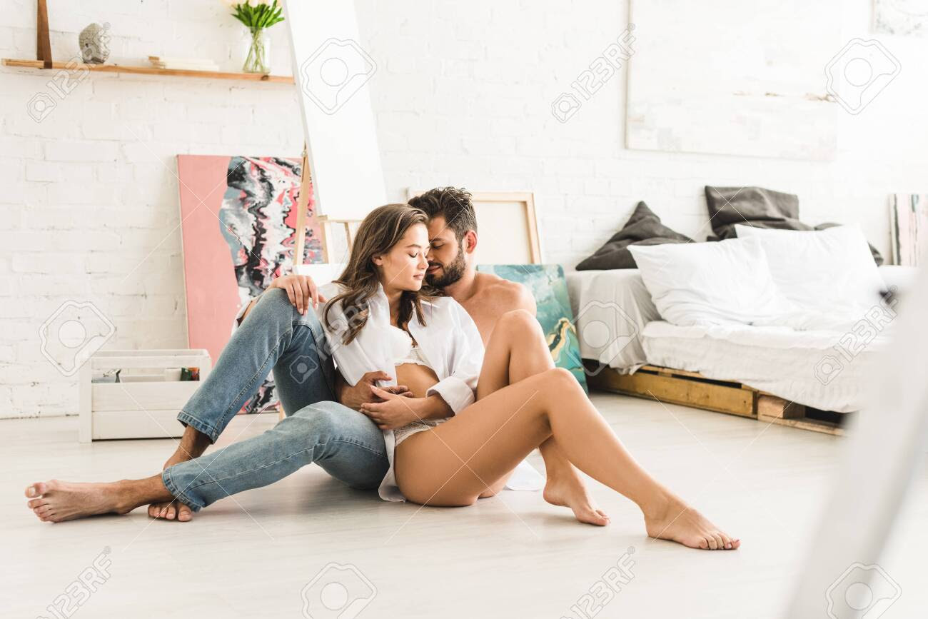 Selective Focus Of Sexy Couple Sitting On Floor While Man Hugging Girl From  Back Stock Photo, Picture And Royalty Free Image. Image 129588404.