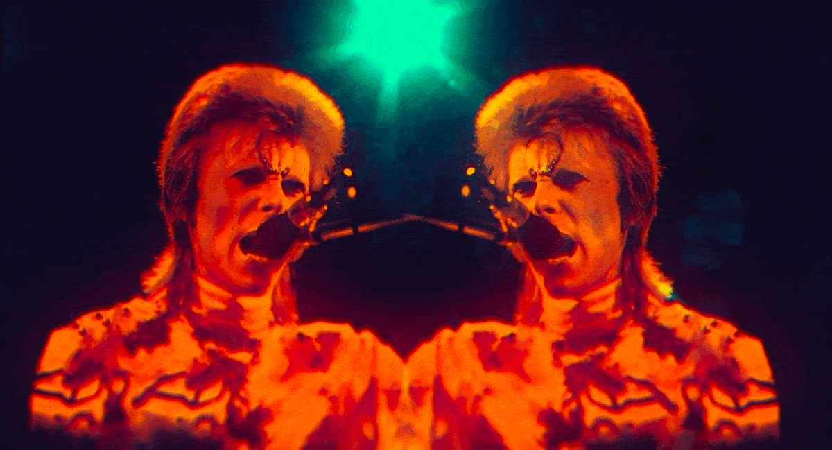 David Bowie on stage singing into a microphone mirrored