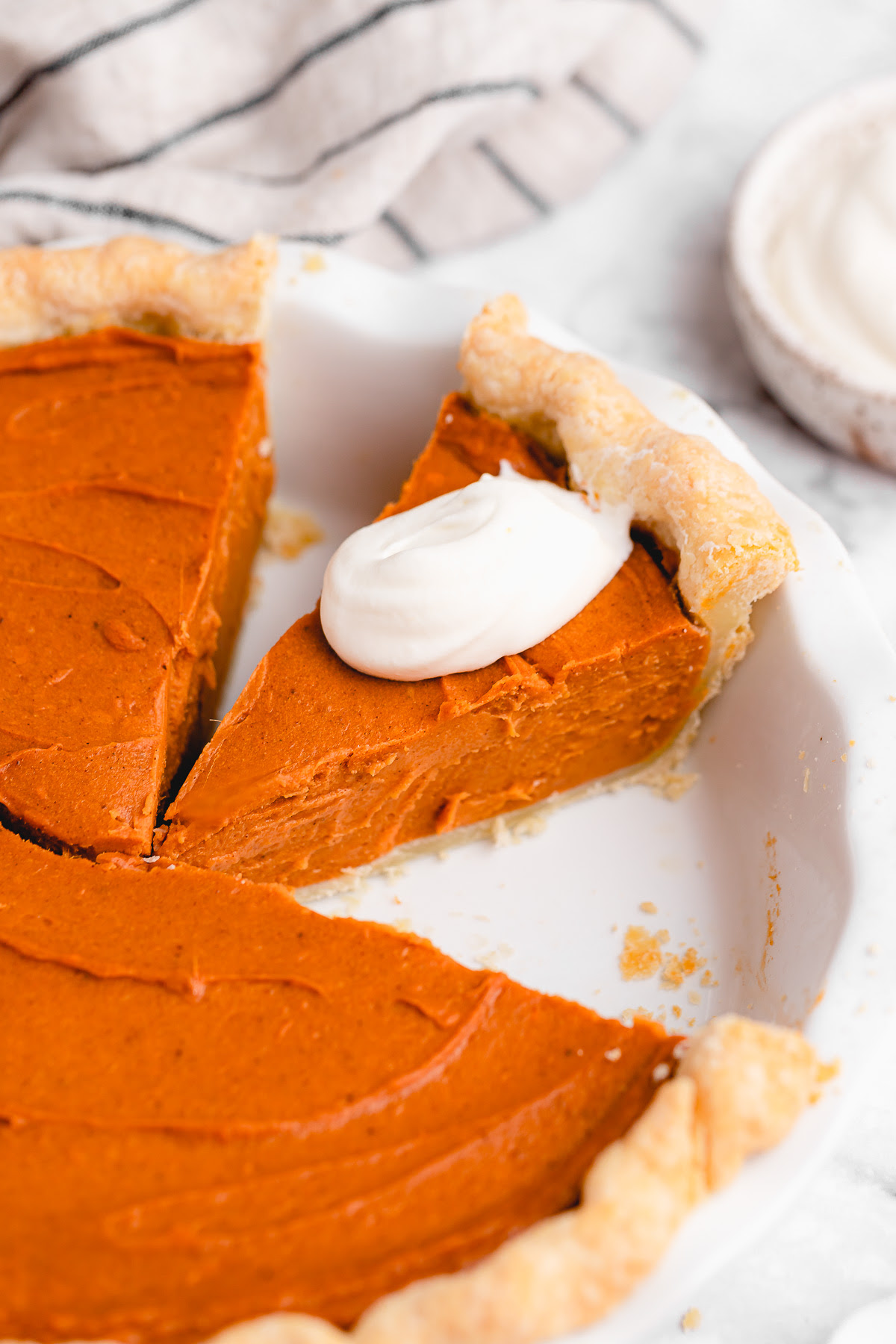 This Vegan Sweet Potato Pie is just like the Southern classic, but made without the dairy and eggs. Sweet, creamy, and perfect! Whole vegan sweet potato pie with slice topped with coconut cream
